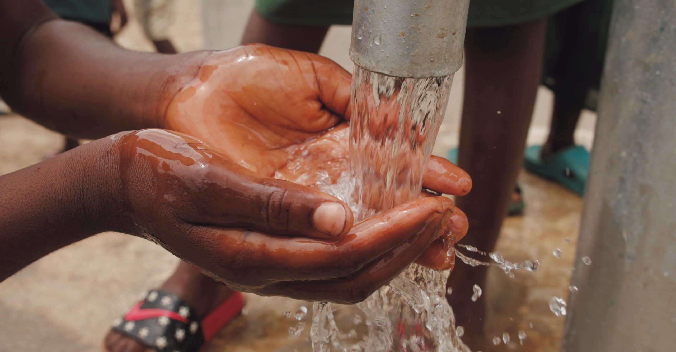 close-up-of-a-child-s-hands-catching-water-from-the-spout-of-3030281